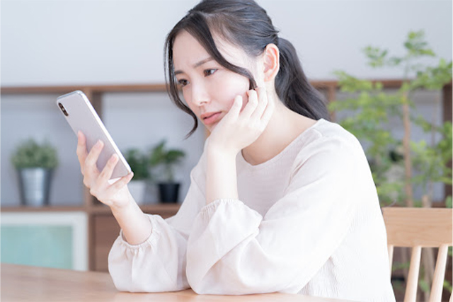 スマホを持って悩む女性